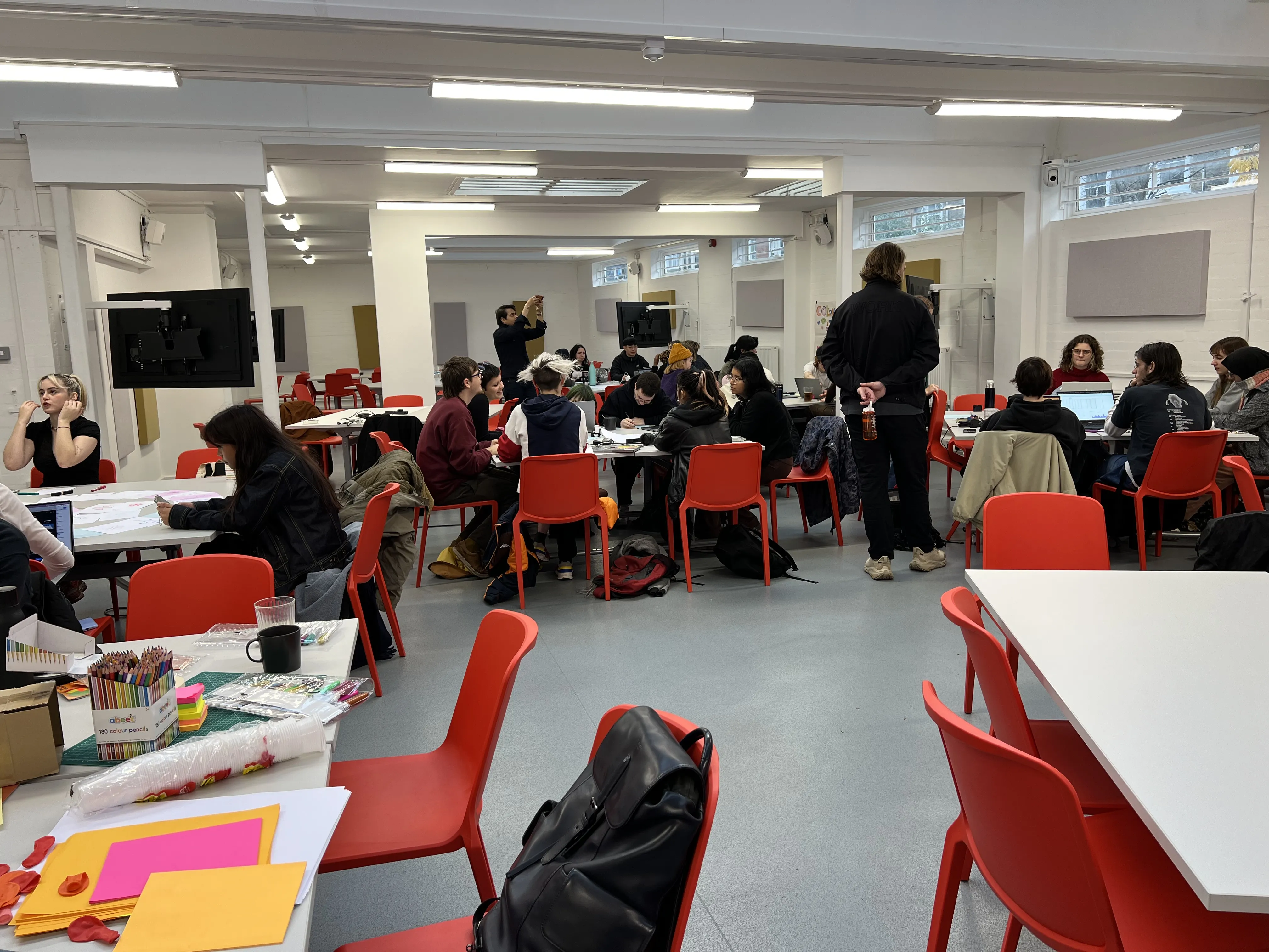 A classroom full of students working together at different tables.