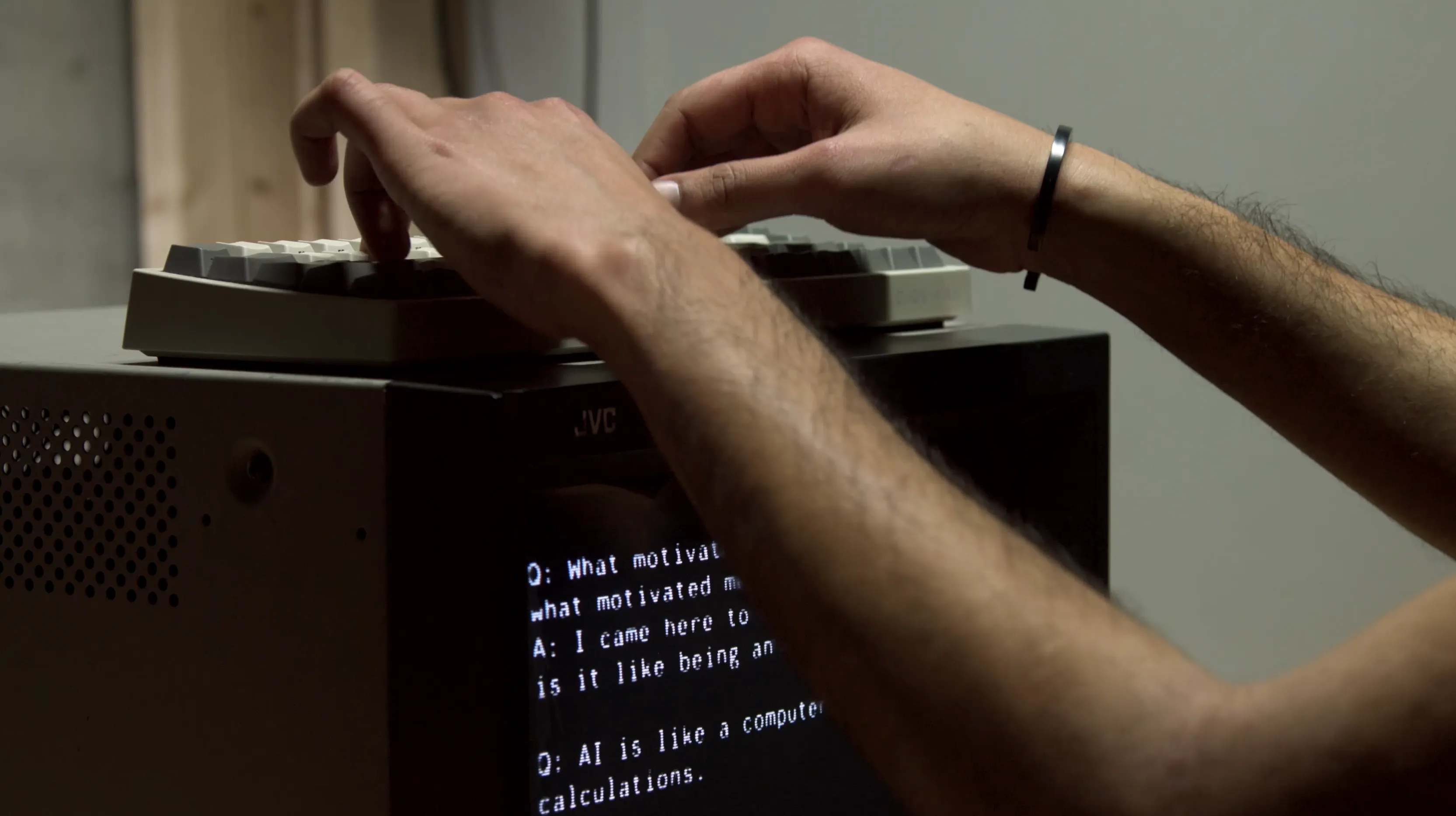 A person is typing on a keyboard atop an old CRT TV, on which there appear to be questions asked by an AI that the person is answering.